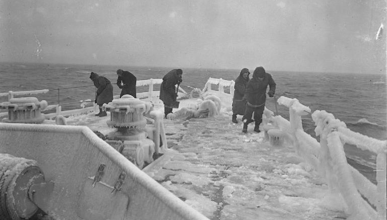 Image:Members of the crew clearing the frozen deck of HMS Inglefield during convoy duty in Arctic waters - a task also endured by seafarers on the convoys' Merchant Navy vessels.  Image: Lt F.A. Hudson / Wikimedia Commons
