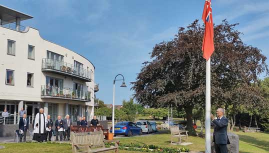 Image:Mariners' Park resident Captain Alex Harrison helped hoist the Red Ensign during the ceremony. Images: Nautilus International