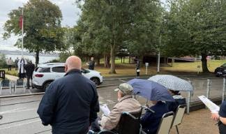 Residents braving the wet weather outside the Trinity House Hub during the service Image:Residents braving the wet weather outside the Trinity House Hub during the service